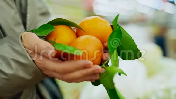 超市里的一个女人手里拿着橘子绿树枝上的橘子在一个女人手里视频的预览图