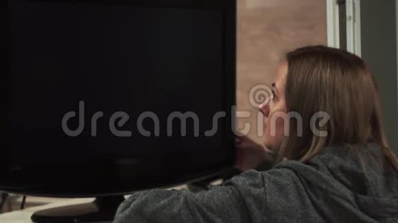 女孩看着蓝色的屏幕电视监视器切换频道视频的预览图