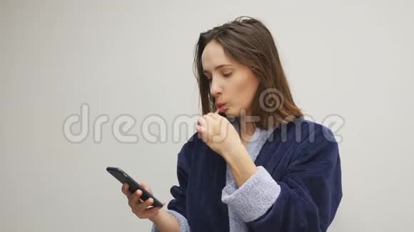 女人早上刷牙看智能手机女性刷牙和滚动新闻线在电话卫生和视频的预览图