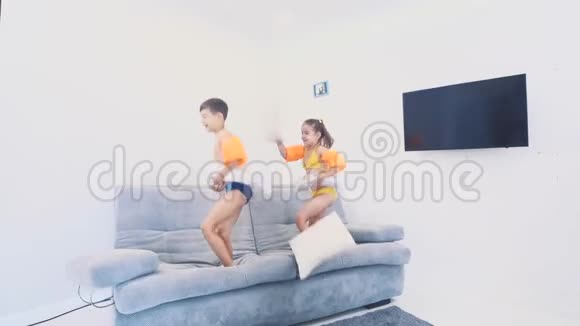 两个穿着泳衣的小朋友很高兴去旅行他们在沙发上跳复制空间4K视频的预览图