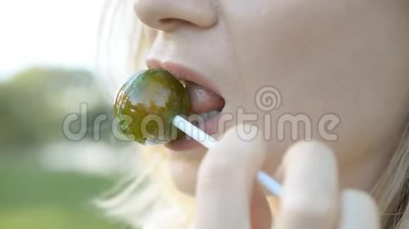女性性感的嘴唇用红色唇膏吸大绿色圆形棒棒糖视频的预览图