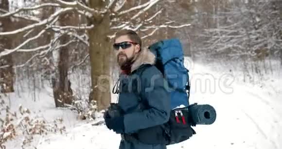 成熟的男人在雪地森林里行走用望远镜视频的预览图
