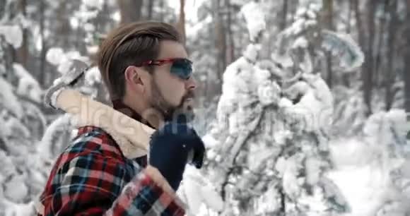 人用斧头在冬林中行走的侧视视频的预览图