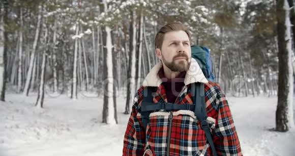 在寒冷的森林里背着一个大背包的大胡子徒步旅行者视频的预览图