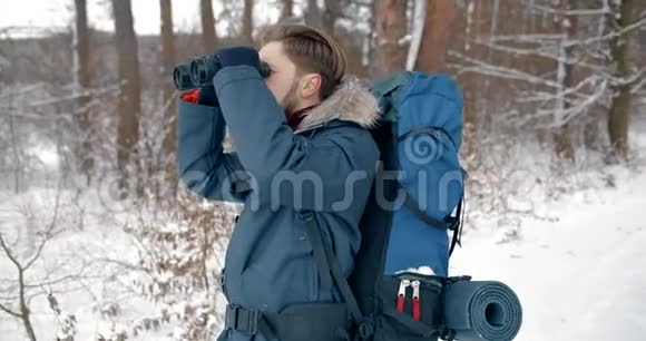 站在雪地森林里看望远镜的人视频的预览图
