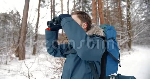 有胡子的人用望远镜在雪地森林里视频的预览图