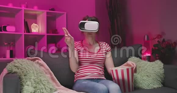 年轻女性晚上佩戴VR耳机触摸虚拟屏幕视频的预览图