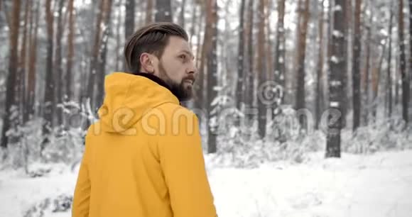 在白雪森林里旅行的有胡子的成熟男人视频的预览图