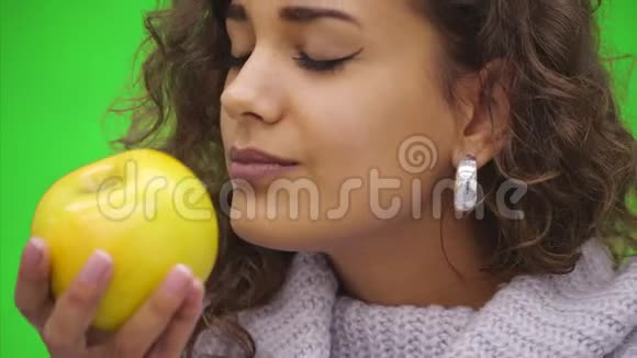 微笑着健康的年轻非洲女人看着一个绿色的苹果咬着它完全快乐快关门复制空间视频的预览图