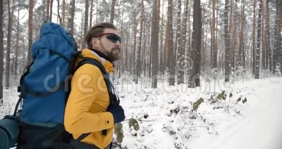 带背包的徒步旅行者在雪地森林中漫步视频的预览图