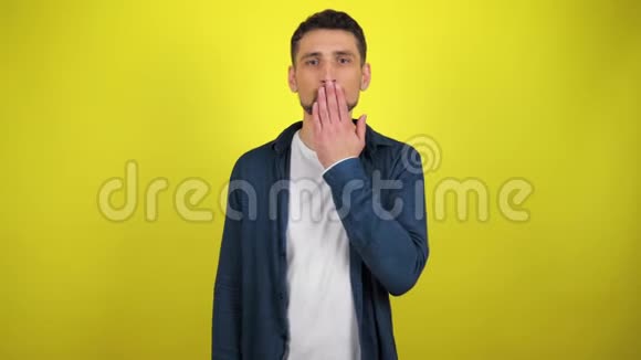 一个穿着蓝色衬衫和白色T恤的年轻人看着摄像机男人吹了一个吻视频的预览图