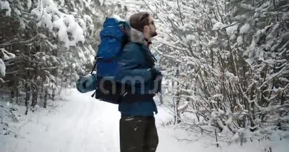 在白雪皑皑的森林里散步时背着背包的成熟男人视频的预览图