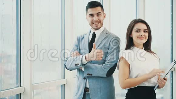 两个商人正微笑着寻找相机拇指手指向上孤立在白色全景背景上关门视频的预览图