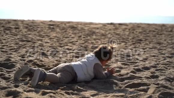 在寒冷多风的日子里孩子在沙滩上住在海岸线上玩沙子西班牙视频的预览图