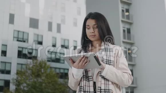 在城市做数字平板电脑的女商人在街上用垫子的漂亮女孩视频的预览图