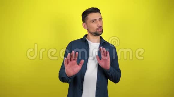 一个穿着蓝色衬衫和白色T恤的年轻人用手做手势表示拒绝视频的预览图