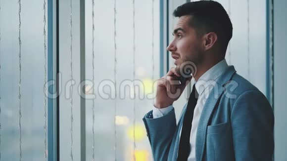 商人站在窗户附近人是隆电话他是孤立的在白色模糊的背景上复制空间4K视频的预览图
