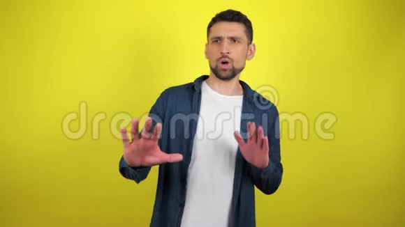 一个穿着蓝色衬衫和白色T恤的年轻人用手做手势表示拒绝视频的预览图