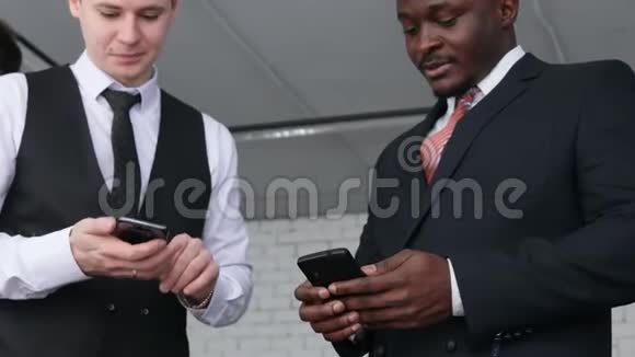 两个男人和智能手机对话穿西装的年轻商人在办公室一起工作和交流视频的预览图