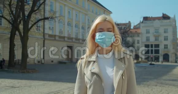 在一个空城中心的冠状病毒期间戴着医疗面具的美丽金发女孩视频的预览图