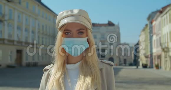 在一个空城中心的冠状病毒期间戴着医疗面具的美丽金发女孩视频的预览图