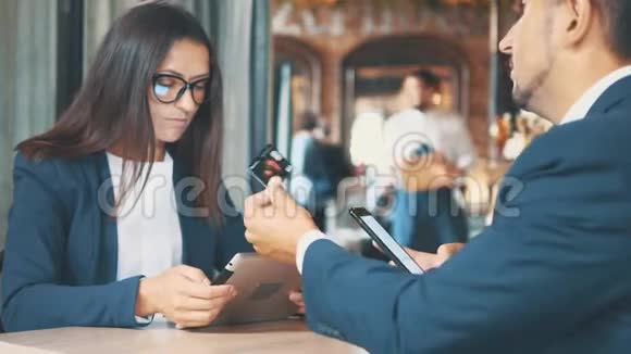 两个穿深蓝色西装的商人正在工作男人给他的伴侣一张购物卡和握手女人是视频的预览图