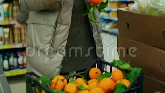 一个女人在超市里选择带绿色树枝的橘子视频的预览图