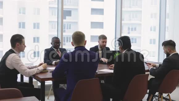 坐在桌边的人的剪影一群年轻的商人在办公室里一起工作和交流视频的预览图