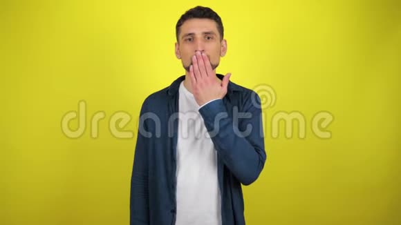 一个穿着蓝色衬衫和白色T恤的年轻人看着摄像机男人吹了一个吻视频的预览图