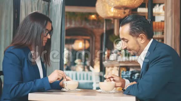 两个商人吃商务午餐在一家餐馆或咖啡店里女人和男人正在搅拌和视频的预览图