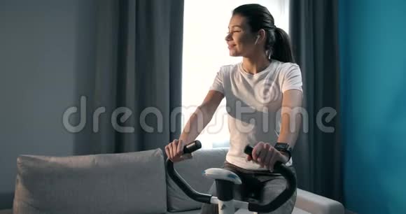 有动力的女孩在家骑自行车锻炼视频的预览图