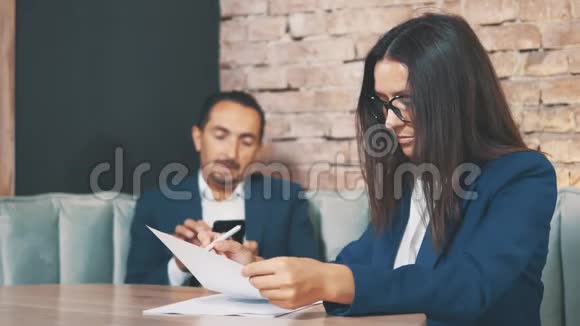 两个商人在一家咖啡馆工作女人正在用心学习文件有人在给别人发语音信息视频的预览图