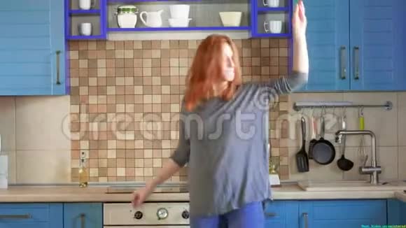 漂亮的红发女孩在家厨房喝早咖啡在家跳舞很有趣红发女人跳舞视频的预览图