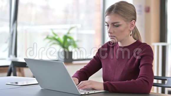 手提电脑的年轻女子在办公室看相机视频的预览图