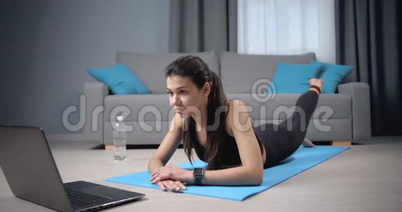 女性在观看笔记本电脑在线培训时锻炼身体视频的预览图
