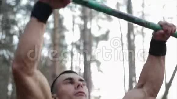 强壮运动员在水平杆上做拉力的特写健美操在森林里工作视频的预览图
