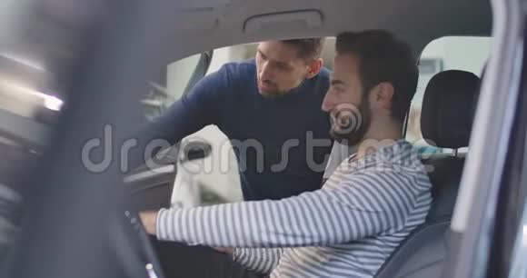 侧面观看白人男子坐在司机座位上听男性汽车经销商解释规格青年视频的预览图