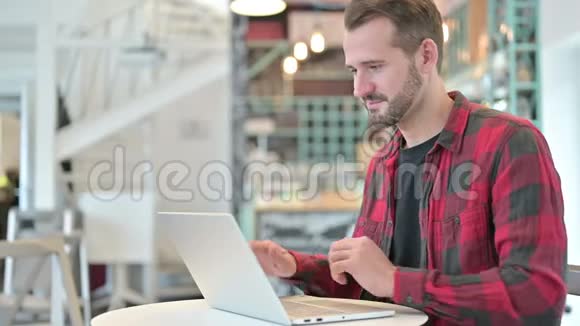 有魅力的年轻人在咖啡厅用电脑聊天视频的预览图