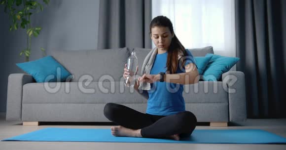 坐在瑜伽垫和饮用水上的运动女孩视频的预览图