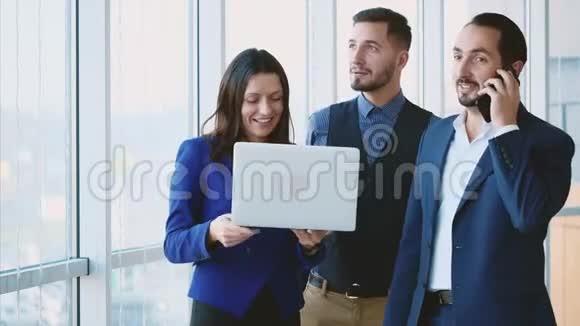男性和女性商业工作者正在讨论问题看着笔记本电脑其中一个在电话里副本视频的预览图