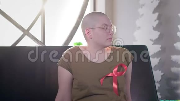 一个患有艾滋病或艾滋病毒的秃头女孩坐在家里穿着红色的丝带化疗后的康复癌症视频的预览图