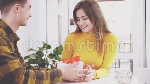 有爱心的男人和一个谦虚的女孩正在阁楼咖啡馆里交谈在咖啡馆里的浪漫约会男人给她心爱的盒子礼物视频的预览图