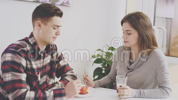 可爱的一对夫妇坐在咖啡馆的桌子旁他正在和他的女朋友交流同时吃甜点真诚真诚视频的预览图