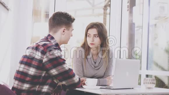 可爱的女孩坐在咖啡馆的桌子旁她正在和男朋友交流男朋友给她看一些东西视频的预览图