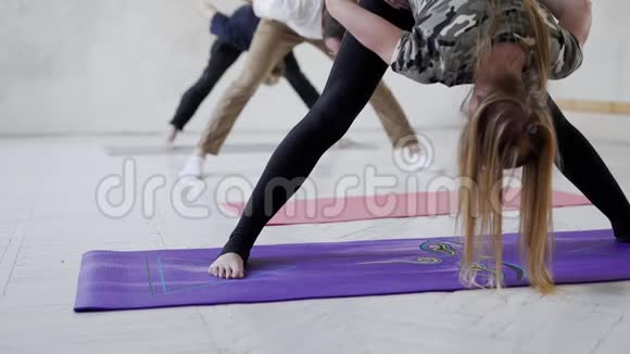 慢动作的年轻人在瑜伽课上练习瑜伽和做伸展运动的腿和背部视频的预览图