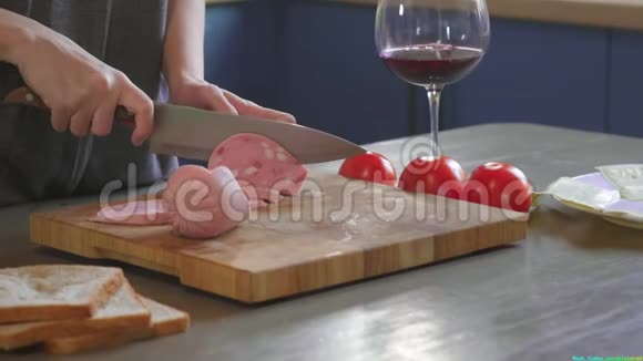 女人在厨房的木板上用锋利的刀把俱乐部三明治切成两半在家里做快餐视频的预览图