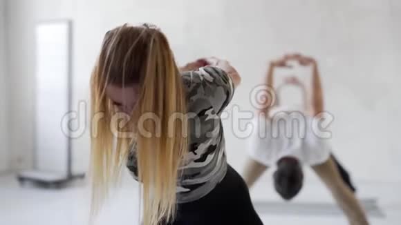 慢动作的年轻人在瑜伽课上练习瑜伽和做伸展运动的腿和背部视频的预览图