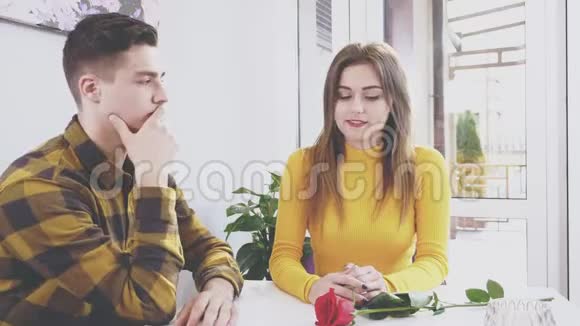 约会年轻夫妇坐在一起女孩正在用她现在的红玫瑰自拍男孩对此感到厌烦视频的预览图