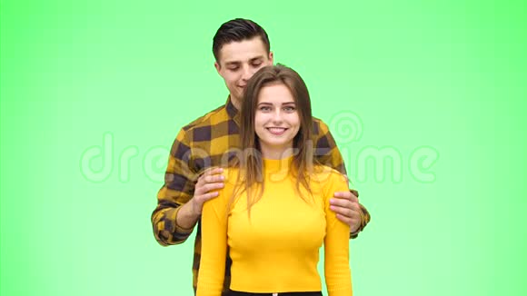 温柔相爱的夫妻正真诚地微笑着依偎在绿色的背景上快关门复制空间4K视频的预览图