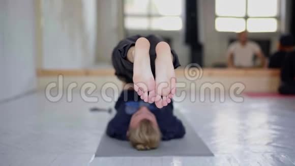 慢动作的年轻人无法辨认的人在轻瑜伽课上练习瑜伽视频的预览图